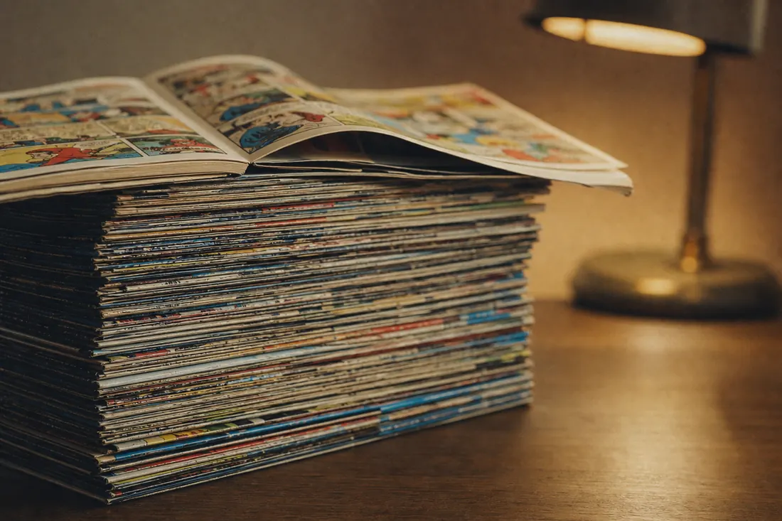 Une pile de livrets grand format ouverts en éventail sur une table claire